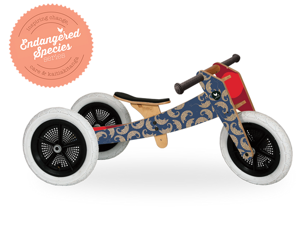 Dark blue and red wooden running trike with pangolin artwork on outside